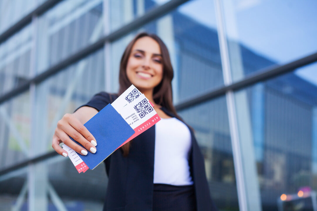 Travel. Woman holding two air ticket in abroad passport near airport.